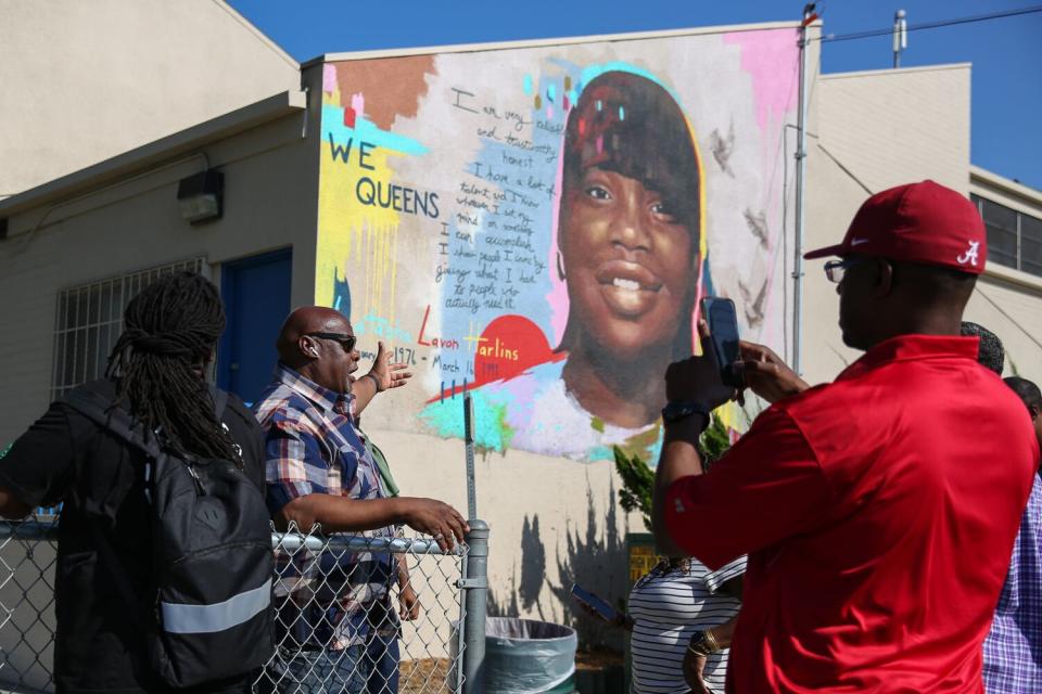 People standing in front of a mural of a Black teenage girl