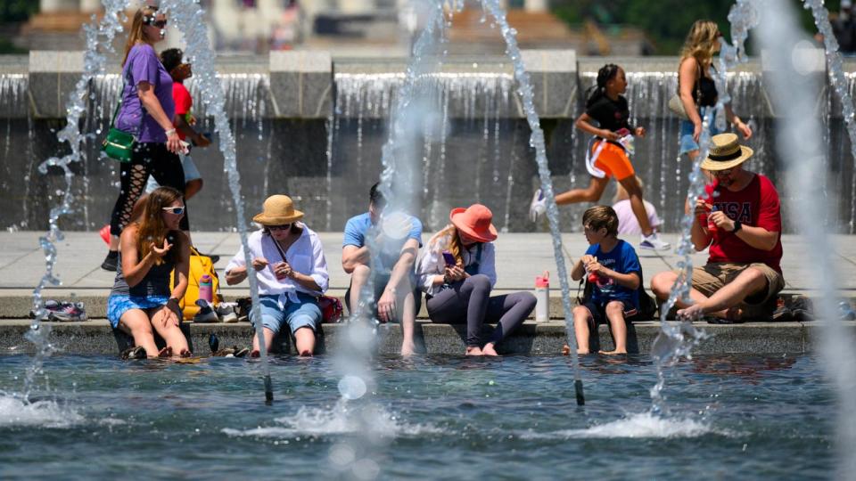 PHOTO: People put their feet in the water to cool off at the US World War II Memorial in Washington, DC, June 19, 2024.  (Drew Angerer/AFP via Getty Images)