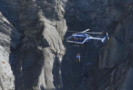 A French Gendarmerie rescue helicopter winches rescue workers over the debris of the Airbus A320 at the site of the crash, near Seyne-les-Alpes, French Alps March 27, 2015. REUTERS/Gonzalo Fuentes