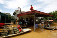 A man (C) sits on rooftop of his flooded house after a heavy rainfall caused by Son Tinh storm in Ninh Binh province, Vietnam. REUTERS/Kham