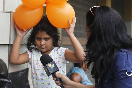 A girl plays with balloons as a reporter tries to interview her, after being deported with her mother from the U.S. at the international airport in San Pedro Sula, northern Honduras July 14, 2014. REUTERS/Jorge Cabrera