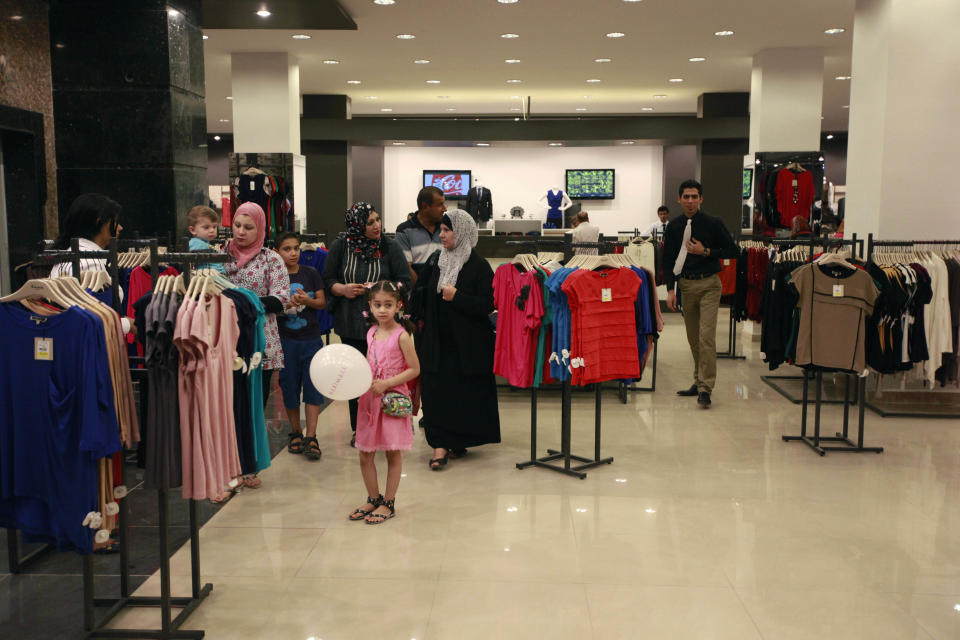 In this Saturday, June 2, 2012 photo, people shop at a department store in Baghdad's Azamiya neighborhood, Iraq. For residents of Azamiya, once one of Baghdad's most violent neighborhoods, the opening of a department store selling party dresses, imported men's suits and designer label perfumes is a hopeful sign that the worst may finally be behind them. (AP Photo/Hadi Mizban)