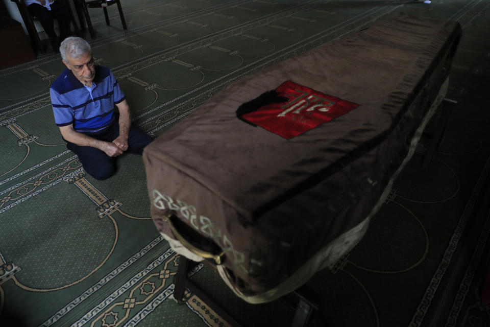 The father of Ibrahim Harb, 35, a Lebanese man who was critically injured in the massive explosion at Beirut's port last year and who died on Monday nearly 14 months after the blast, prays at a mosque at his son's coffin in Beirut, Lebanon, Tuesday, Sept. 28, 2021. On Aug. 4, 2020, hundreds of tons of ammonium nitrate, a highly explosive material used in fertilizers, ignited after a massive fire at the port. The death brings to at least 215 the number of people who have been killed by the blast, according to official records. (AP Photo/Hussein Malla)