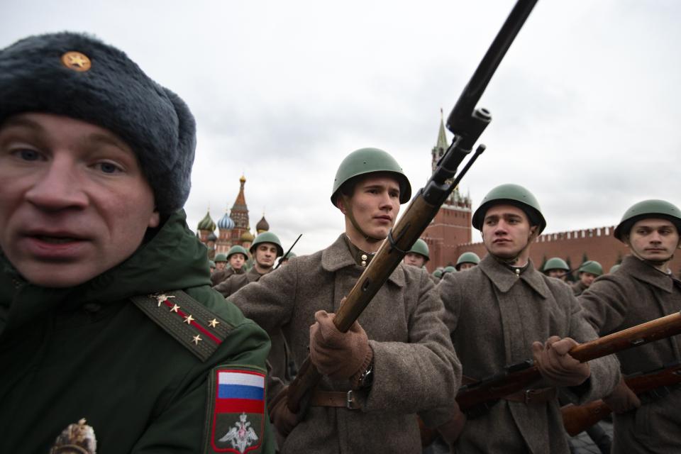 A Russian military police officer, left, escorts Russian soldiers dressed in Red Army World War II winter uniforms as they take a part in a reconstruction of a World War II-era parade in Moscow's Red Square, Russia, Thursday, Nov. 7, 2019. The Nov. 7, 1941 parade saw Red Army soldiers move directly to the front line in the Battle of Moscow, becoming a symbol of Soviet valor and tenacity in the face of overwhelming odds. (AP Photo/Alexander Zemlianichenko)
