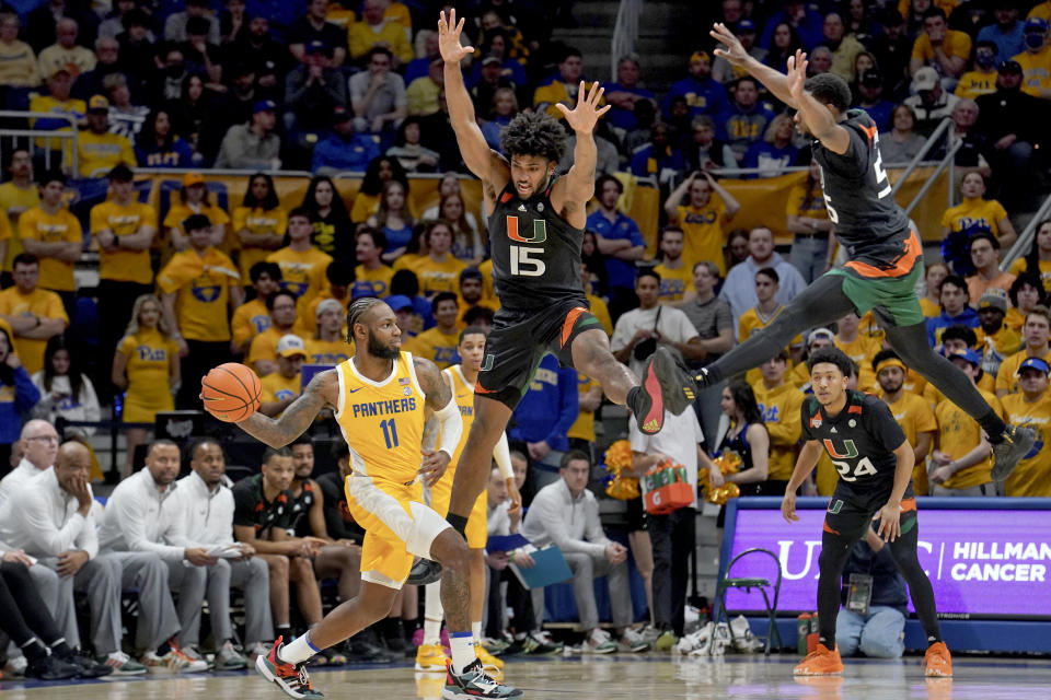 Pittsburgh guard Jamarius Burton looks to pass around Miami forward Norchad Omier (15) and guard Wooga Poplar (55) during the first half of an NCAA college basketball game in Pittsburgh, Saturday, Jan. 28, 2023. (AP Photo/Matt Freed)