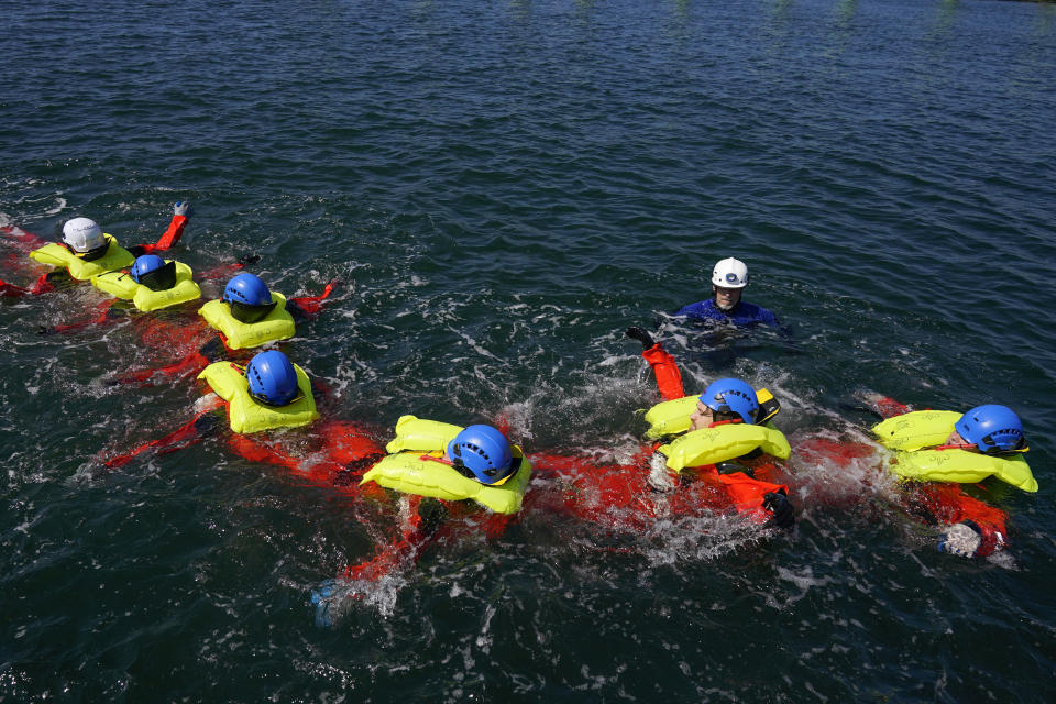 Participants in a Global Wind Organisation certification class learn how to do a group survival float at the Massachusetts Maritime Academy in Bourne, Mass., Thursday, Aug. 4, 2022. At the 131-year-old maritime academy along Buzzards Bay, people who will build the nation's first commercial-scale offshore wind farm are learning the skills to stay safe while working around turbines at sea. (AP Photo/Seth Wenig)