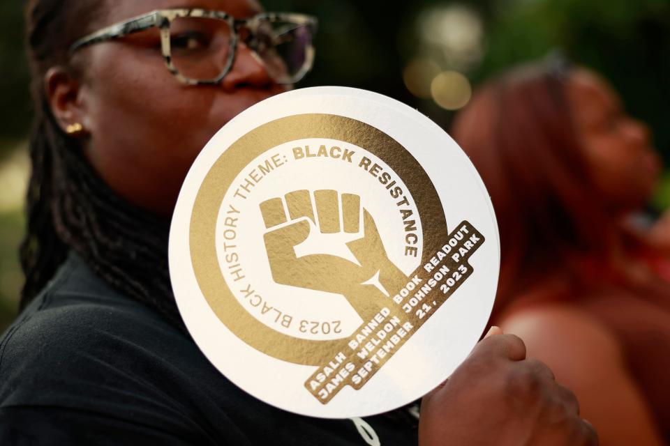 During a "Banned Book Readout" Thursday at James Weldon Johnson Park, Shirletta Kinchen, an associate professor at the University of Lousville, uses a fan carrying a logo for this year's national conference of the 108-year-old Association for the Study of African American Life and History (ASALH), which is meeting downtown.