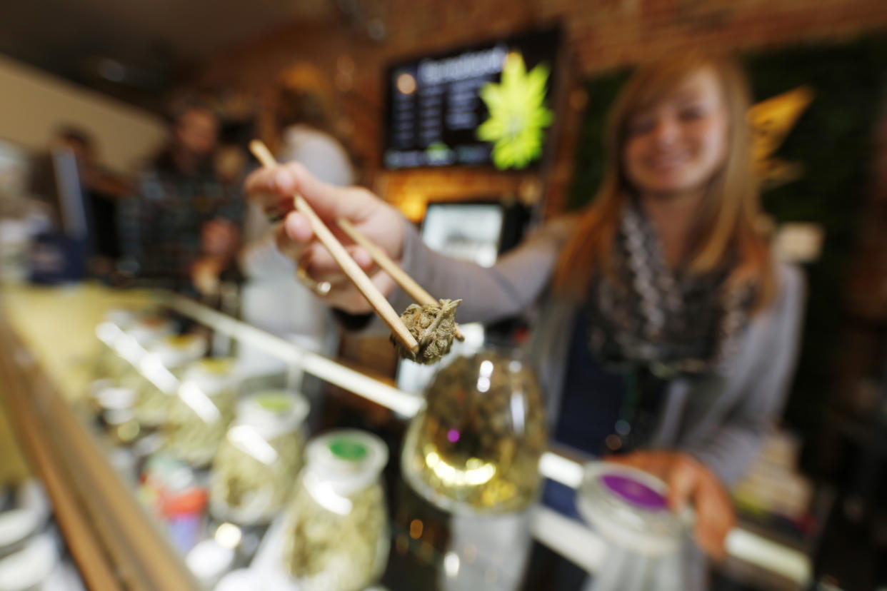 In this Friday, Dec. 18, 2015, photograph, LivWell store manager Carlyssa Scanlon shows off some of the products available in the marijuana line marketed by rapper Snoop Dogg in one of the marijuana chain's outlets south of downtown Denver. LivWell grows the Snoop pot alongside many other strains on its menu. (AP Photo/David Zalubowski)