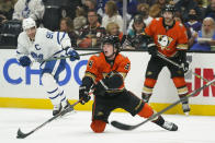 Anaheim Ducks' Jamie Drysdale, center, hits the puck as Toronto Maple Leafs' John Tavares, background left, watches during the first period of an NHL hockey game Sunday, Nov. 28, 2021, in Anaheim, Calif. (AP Photo/Jae C. Hong)