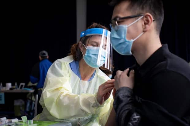 Kenny Huynh, 24, gets his first dose of the Moderna COVID-19 vaccine from Dr. Rachel Spitzer at a temporary clinic for residents of Toronto’s Jane and Finch neighbourhood earlier this year. (Evan Mitsui/CBC - image credit)