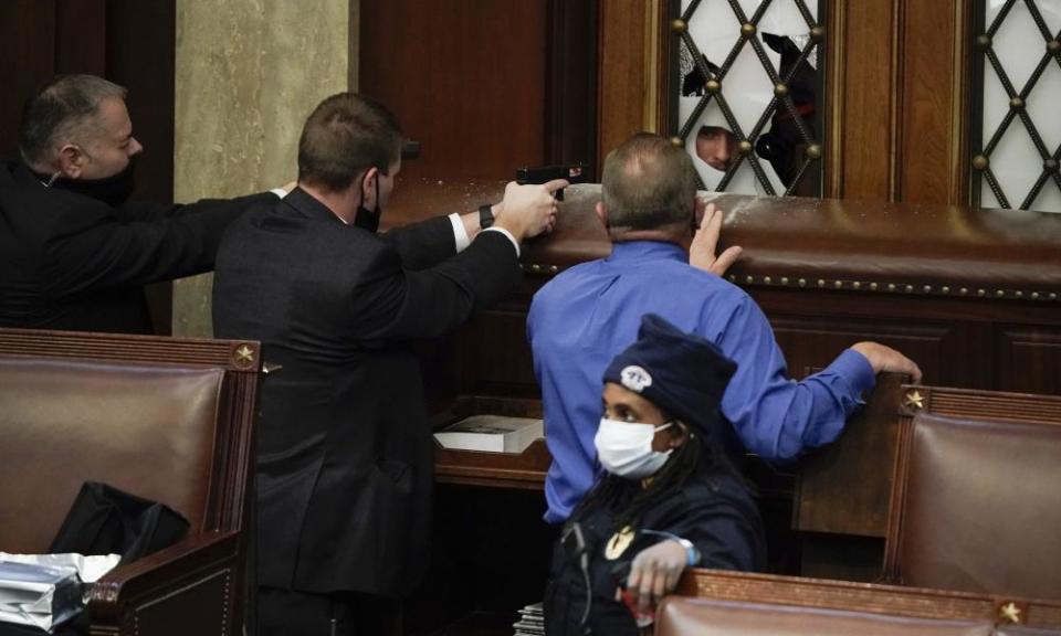 Police with guns drawn watch as protesters try to break into the House chamber at the US Capitol.