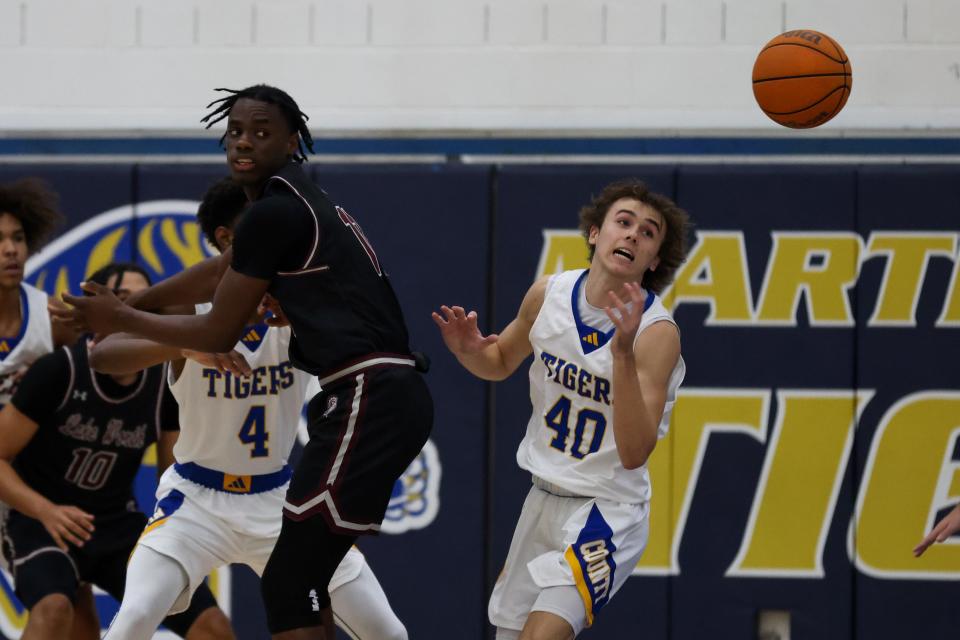 Paul Stemle (40), of Martin County, and Hedrens Bartelus (11), of Lake Worth, chase down a loose ball in a high school boys basketball game, Tuesday, Dec. 5, 2023, at Martin County High School.