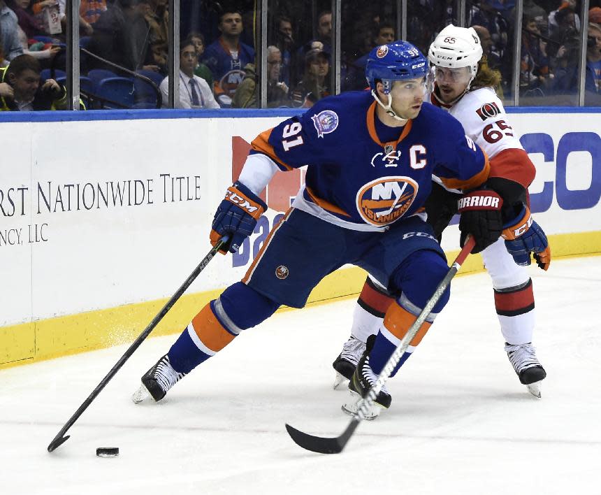 Ottawa Senators defenseman Erik Karlsson (65) tries to take the puck away from New York Islanders center John Tavares (91)in the second period of an NHL hockey game at Nassau Coliseum on Tuesday, Dec. 2, 2014, in Uniondale, N.Y. (AP Photo/Kathy Kmonicek)