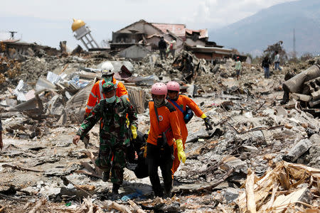 Rescue workers and a soldier remove a victim of last week's earthquake in the Balaroa neighbourhood in Palu, Central Sulawesi, Indonesia October 6, 2018. REUTERS/Darren Whiteside