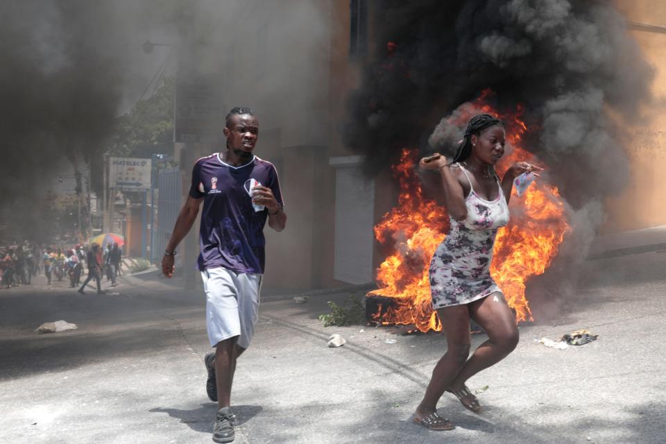 Demonstrators run past tires set on fire during a protest against insecurity in Port-au-Prince, Haiti, on Aug. 7, 2023.