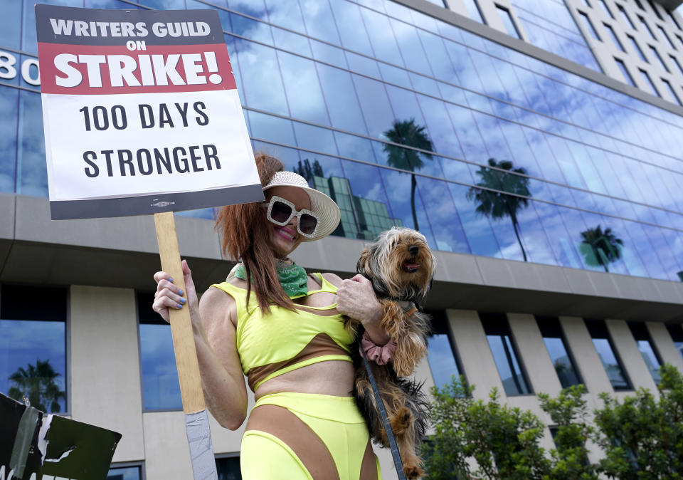 Phoebe Price lleva a su perro Arnold junto con un cartel en una protesta frente a los estudios de Netflix el miércoles 9 de agosto de 2023 en Los Ángeles. La huelga de guionistas de Hollywood alcanzó hoy la marca de los 100 días, las industrias del cine y la televisión de Estados Unidos siguen paralizadas por huelgas de guionistas y actores. (Foto AP/Chris Pizzello)