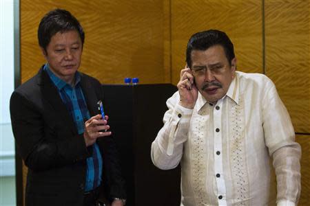 Manila mayor Joseph Estrada (R) speaks on his phone before a news conference in Hong Kong April 23, 2014. REUTERS/Tyrone Siu