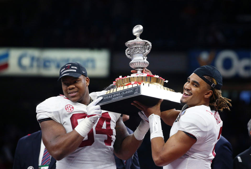 Alabama quarterback Jalen Hurts (2) and defensive lineman Da’Ron Payne (94) hoist the bowl trophy after defeating Clemson in the Sugar Bowl. (AP Photo/Butch Dill)