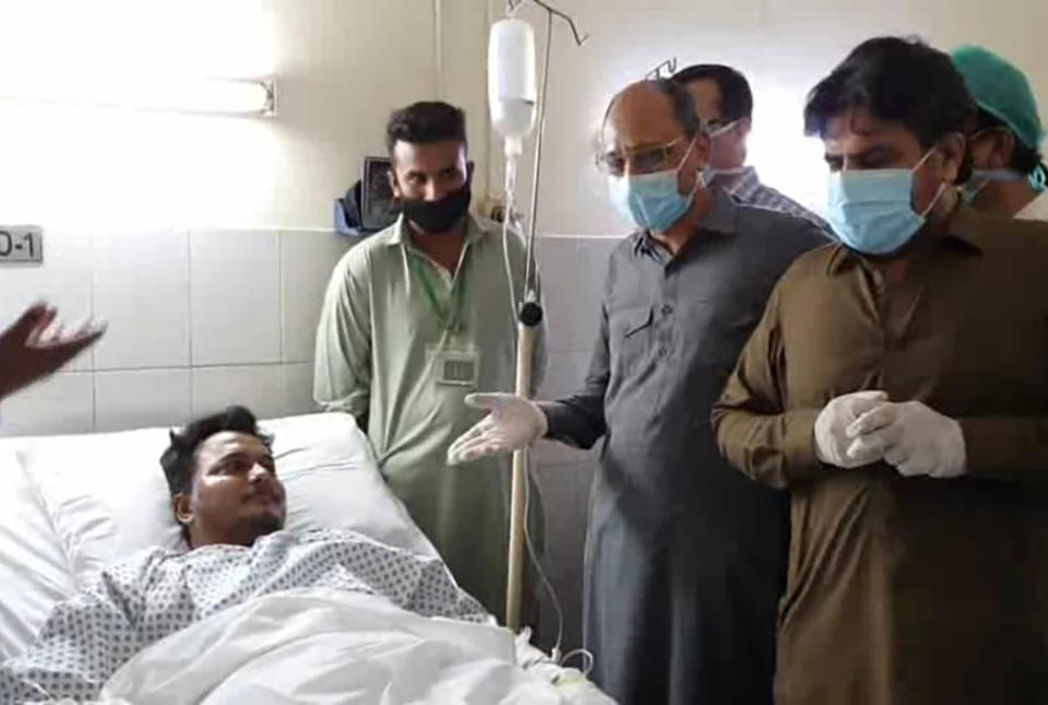 In this photo released by the Sindh Press Information Department, Pakistani provincial minister Saeed Ghani, second from right, meets Mohammad Zubair who survived a plane crash, at a hospital in Karachi, Pakistan, Friday, May 22, 2020. An aviation official says a passenger plane belonging to state-run Pakistan International Airlines carrying passengers and crew has crashed near the southern port city of Karachi. ((Sind Press Information Department, via AP)