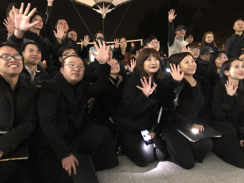 In this Tuesday, Dec. 10, 2019 photo, members of a theater troupe raise their hands to symbolize the five demands of pro-democracy protesters after a performance of Les Miserables in at an outdoor event space in Hong Kong. A Hong Kong theater troupe is making audiences weep by touring a stirring production of 'Les Miserables.' Based on Victor Hugo's tale of rebellion in 19th-century France, the rousing music and lyrics of struggle and resistance struck chords with audience members emotionally and physically drained after six months of protests that have convulsed the city. (AP Photo/John Leicester)