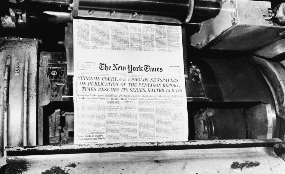 A printing press spits out of a copy of a newspaper.