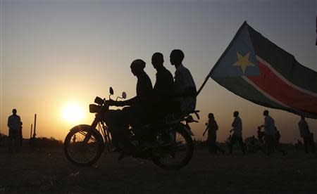 Men ride on a motorbike with South Sudan's national flag as they celebrate referendum results in Abyei October 31, 2013. REUTERS/Goran Tomasevic