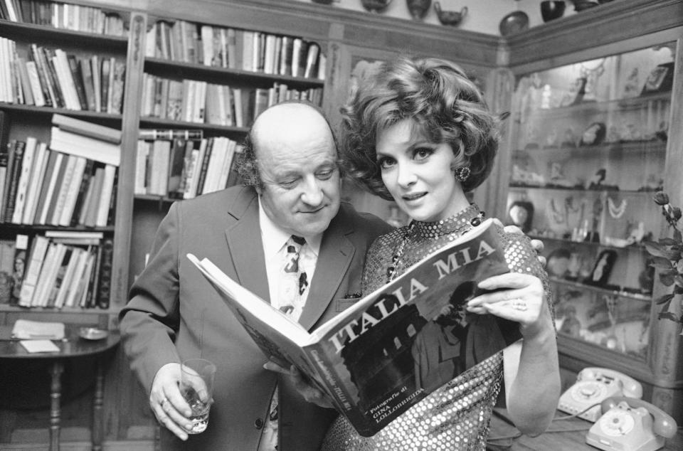 FILE - Italian sculptor Giacomo Manzu looks at the book "Italia Mia" held by Gina Lollobrigida in her villa in Rome, Dec. 1, 1972 when the star presented it to the press and some art personalities her book - a selection of pictures of Italy which took her two years to complete and edit. Lollobrigida has died in Rome at age 95. Italian news agency Lapresse reported Lollobrigida’s death on Monday, Jan. 16, 2023 quoting Tuscany Gov. Eugenio Giani. (AP Photo/Giulio Broglio, File)