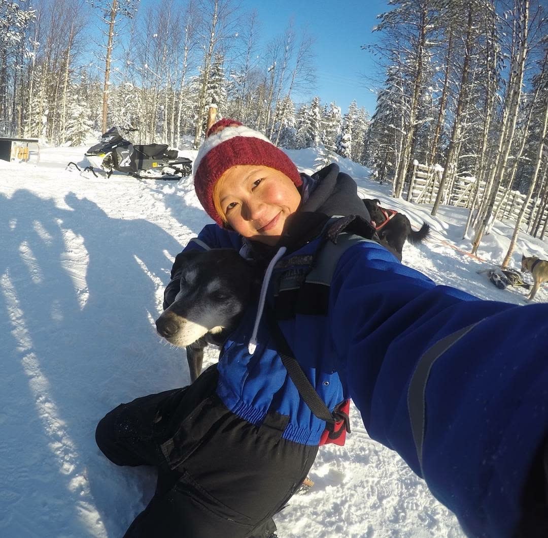 Lady on a solo female travel trip, smiling at camera with a husky
