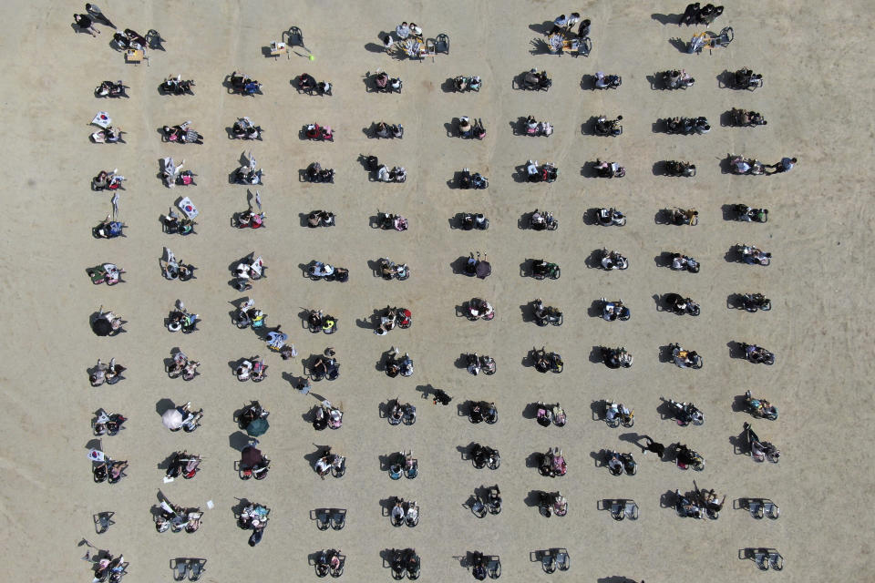 First grade students and their parents maintain social distancing during a welcome ceremony at DunSan elementary school in Daejeon, South Korea, Wednesday, May 27, 2020. More than 2 million high school juniors, middle school seniors, first- and second-grade elementary school children and kindergartners were expected to return to school on Wednesday. (Kim Jun-bum/Yonhap via AP)