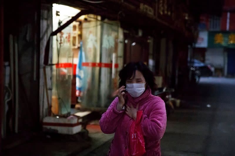 Woman wears a face mask in a market alley in Jiujiang