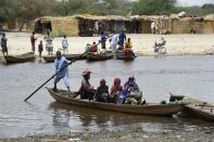 People cross a creek in N'Bougoua on the edge of Lake Chad on April 6, 2015