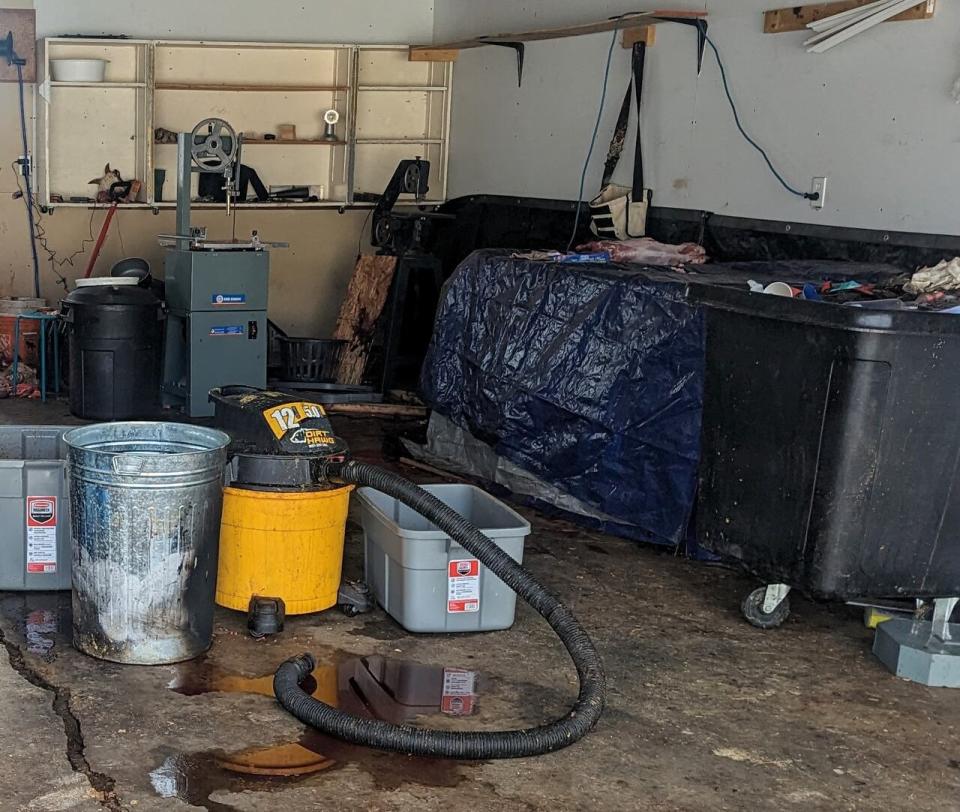 Butchered meat sits on top of a tarp-covered table inside the garage.