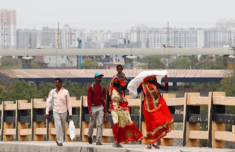A migrant worker carries her daughter as she walks on a highway with others looking out for a transport to return to their villages, after India ordered a 21-day nationwide lockdown to limit the spreading of coronavirus disease (COVID-19), in Ghaziabad