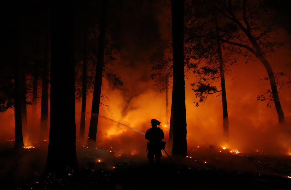 A firefighter sprays water to control a fire in California amid the state’s most destructive wildfire since record-keeping began. Source: AP Photo/John Locher