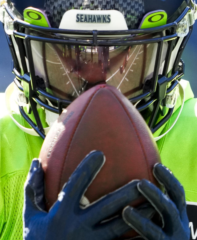 Seattle Seahawks players, including running back Kenny McIntosh (25) and  wide receiver Tyjon Lindsey (81), run onto the field for warmups before the  NFL football team's mock game, Friday, Aug. 4, 2023