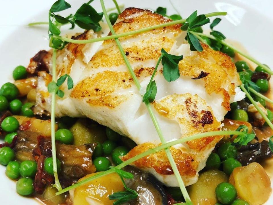 Plate of seared cod over vegetables.