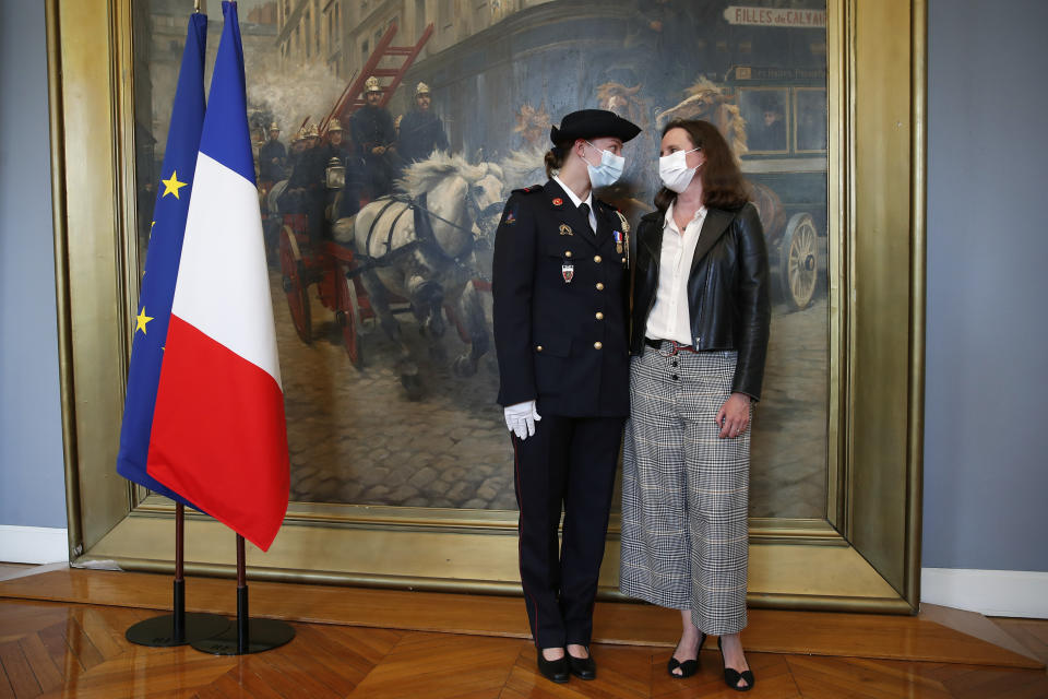 French math teacher-volunteer fighter, Marion Dehecq, left, poses with Paris-based Associated Press journalist Lori Hinnant, after she receives a bronze medal for courage and dedication as she used CPR to save the life of a jogger, during a ceremony with France's minister for citizenship issues, Marlene Schiappa at the Paris fire service headquarters in Paris, France, Monday, May 10, 2021. The jogger's wife, Paris-based Associated Press journalist Lori Hinnant, helped identify the anonymous rescuer by putting up thank-you signs in Monceau Park, where her husband Peter Sigal went into cardiac arrest on April 28. (AP Photo/Francois Mori, pool)