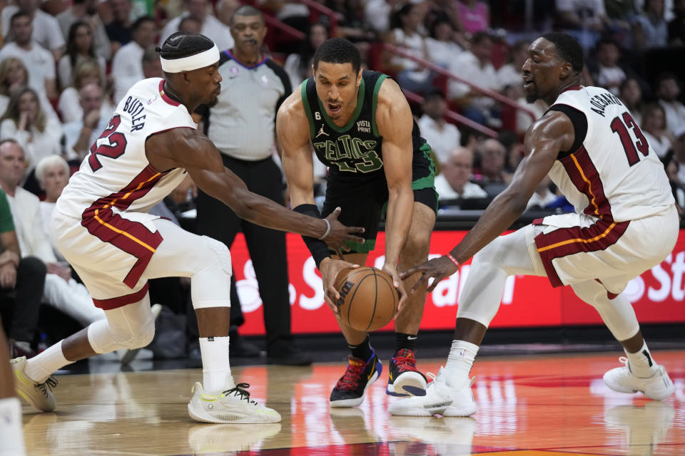 Miami Heat center Bam Adebayo (13) and forward Jimmy Butler (22) defend Boston Celtics guard Malcolm Brogdon (13) during the second half of Game 3 of the NBA basketball playoffs Eastern Conference finals, Sunday, May 21, 2023, in Miami. (AP Photo/Wilfredo Lee)