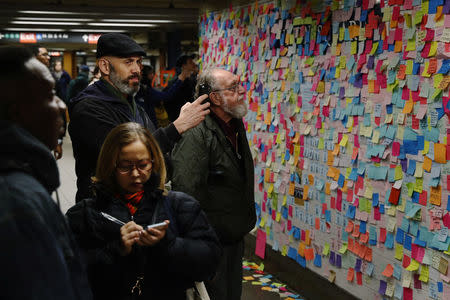 Commuters stop to read and photograph messages written on post-it notes regarding the election of President-elect Donald Trump in New York, U.S., November 15, 2016. REUTERS/Lucas Jackson