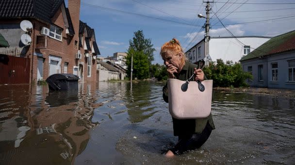 PHOTO: A local resident makes her way through a flooded road after the walls of the Kakhovka dam collapsed overnight, in Kherson, Ukraine, June 6, 2023. (Evgeniy Maloletka/AP)