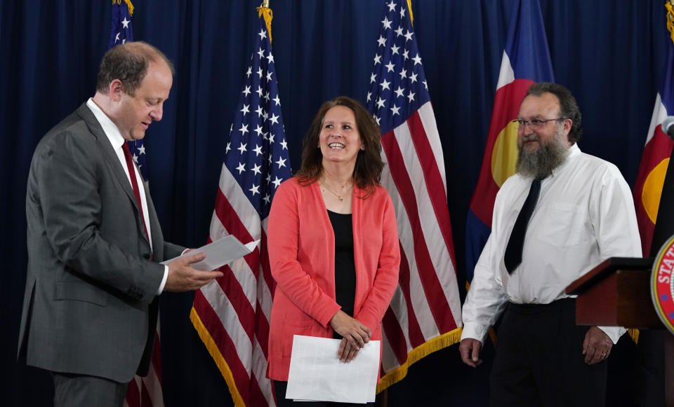 Sally Sliger, center, Colorado's first $1-million winner for receiving the COVID-19 vaccine, and her husband, Chris, right, joke with Colorado Governor Jared Polis during a news conference to announce the awarding of the prize Friday, June 4, 2021, at the governor's mansion in Denver. Colorado will award four more $1-million prizes in the next month to residents who have been vaccinated. (AP Photo/David Zalubowski)