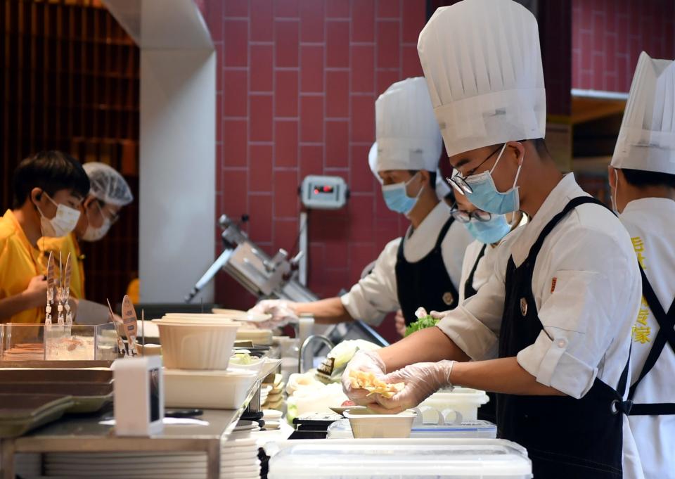 Staff members prepare meals for the customers at a restaurant in Zhengzhou, central China's Henan Province, Aug. 29, 2021. Zhengzhou started on Saturday to allow restaurants to resume dine-in service, while requiring them to conduct regular disinfection, shorten dining hours and provide serving chopsticks and spoons.   Customers and takeaway deliverymen are requested to undergo temperature and health codes scanning before entering restaurants.    Zhengzhou city cleared all its medium- and high-risk areas for COVID-19 on Saturday, with closed-management measures in affected areas lifted, reported the city authorities. (Photo by Li Jianan/Xinhua via Getty Images)