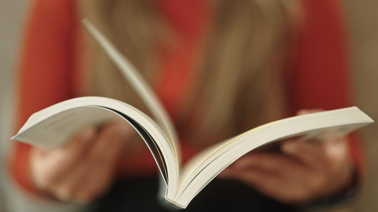 A person out of focus reading a book