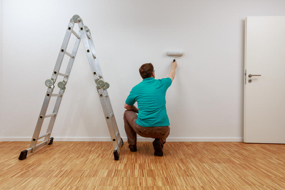 Man is painting a wall white