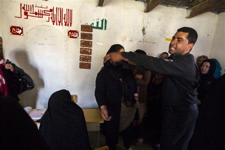 An Afghan police officer tries to control the crowd as women wait to receive their voter cards at a voter registration centre in Kabul March 30, 2014. The Afghan presidential elections will be held on April 5.REUTERS/Zohra Bensemra