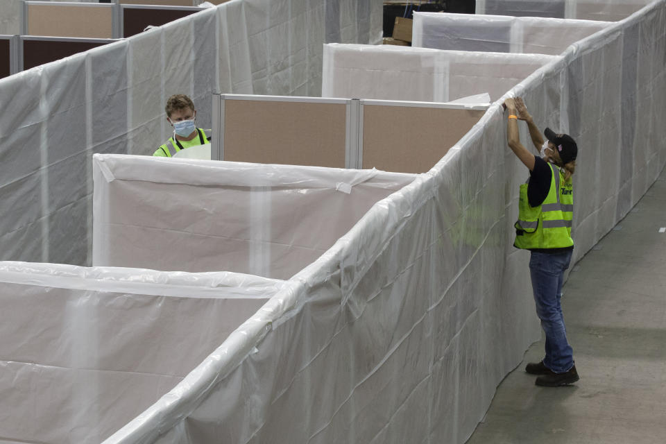 FILE — In this April 18, 2020 file photo sheeting is placed on partitions installed between beds as work is performed to turn the Sleep Train Arena into a 400 bed emergency field hospital to help deal with the coronavirus , in Sacramento, Calif. California spent nearly $200 million to set up, operate and staff alternate care sites that ultimately provided little help when the state’s worst coronavirus surge spiraled out of control last winter, forcing exhausted hospital workers to treat patients in tents and cafeterias. (AP Photo/Rich Pedroncelli, File)