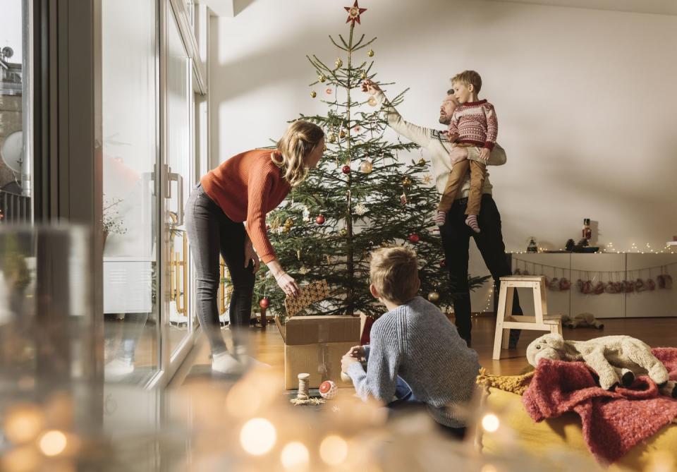 family of four decorating their christmas tree