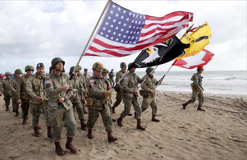 <p>Men dressed with U.S. 101st Airborne Division uniforms walk on the beach during commemorations marking the 73th anniversary of D-Day, the June 6, 1944, landings of Allied forces in Normandy. (Photo: Chesnot/Getty Images) </p>