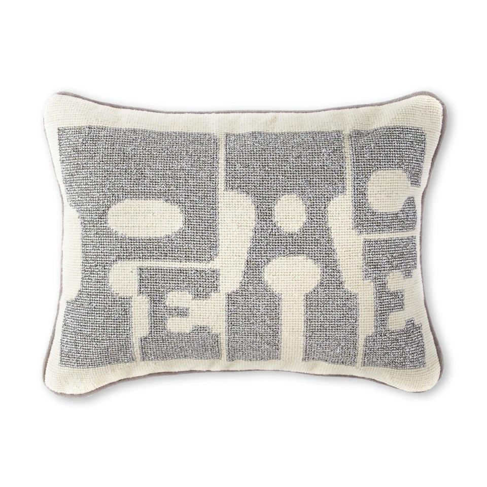 In this photo provided by JCPenney, Jonathan Adler’s needlepointed Peace pillow adds a holiday message in a hip way. Following the general trend in home decor, holiday trim and accessories this year are a mix of eclectic and traditional colors and styles. Style watchers say we’re approaching the holidays with a more open mind, and decor has never been more expansive in terms of what works. (AP Photo/JCPenney, Keith Madigan Studios)