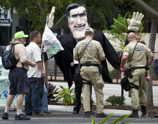 Police officers check the documents of protesters carrying an effigy of US Republican Party presidential candidate Mitt Romney during a demonstration in downtown Tampa, Florida, on August 26, 2012. Due to incoming severe weather and possible hurricane conditions expected to hit the state by Monday, the Republicans have decided to cut short their National Convention by one day